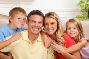 Family of four sitting on a couch and hugging