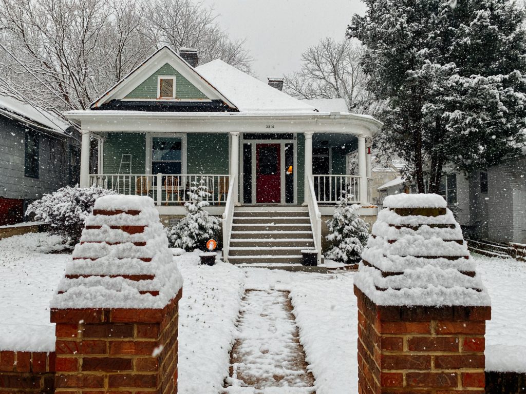 Suburban home with snow covering yard and roof.