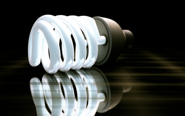 Spiral-shaped, energy-saving LED light bulb on dark surface with black background.